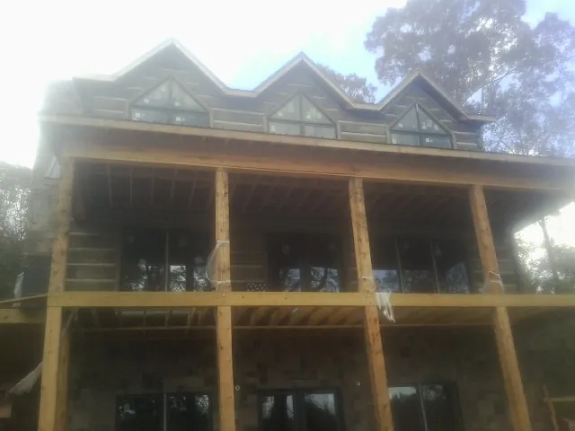 Dormers and porch framing on a large log home under construction — Roof Coating work by our crew in Colton