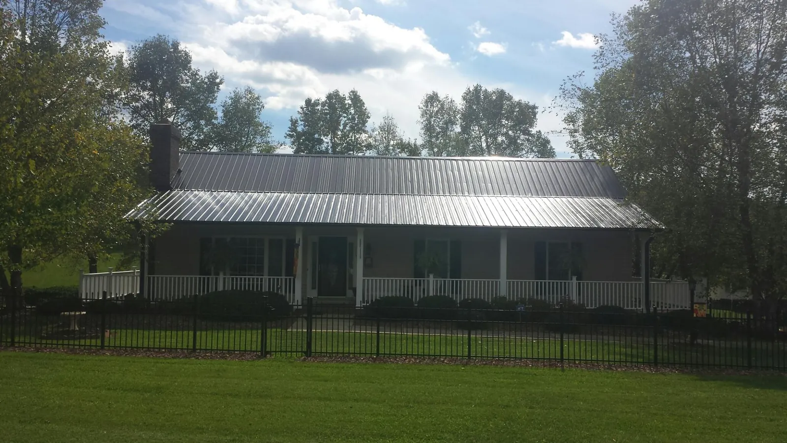 Gray metal roof on a brick ranch with a full width front porch — Gutter Guard Installation work by our crew in Colton